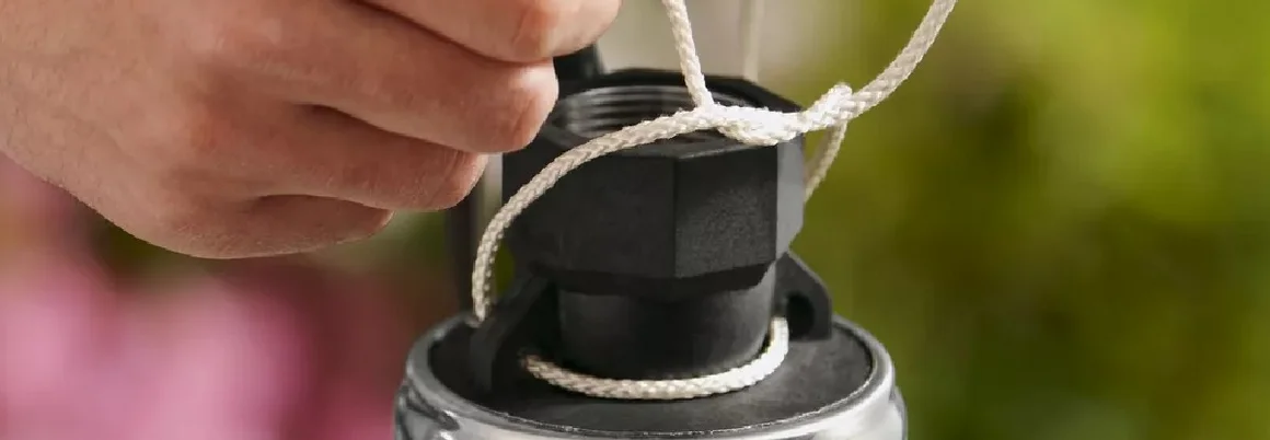 Hände binden eine Schnur um ein Rohr.